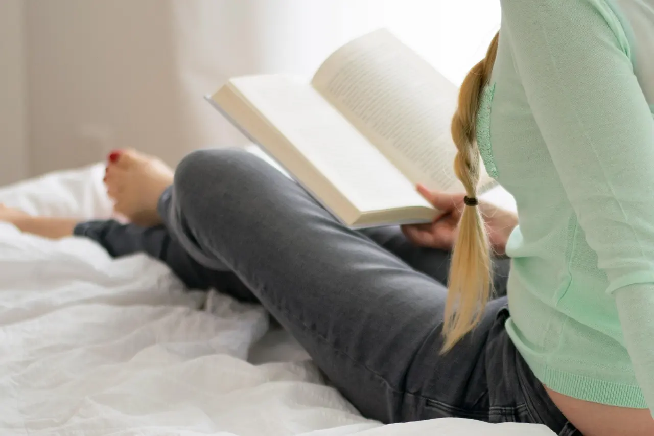 Stock photo: woman reading in bed in a cozy bedroom